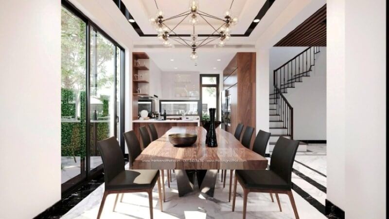 Không chỉ là nơi để mọi người thưởng thức những tinh hoa ẩm thực từ người mẹ, người vợ, người bà,.. mà còn là nơi để gia đình vun đắp nên mái ấm hạnh phúc. Việc chú tâm vào trang trí một không gian phòng ăn biệt thự lại càng được chú trọng để tạo nên điều kiện tốt nhất cho tất cả mọi người trong gia đình. Việc bố trí, lựa chọn đồ nội thất hợp với lối sống, gu thẩm mỹ và bố trí ánh sáng lại ngày càng được chú trọng. Tùy từng sở thích của mỗi gia đình mà sẽ có những ý tưởng bố trí nội thất phòng ăn phù hợp chẳng hạn với ý tưởng thiết kế nội thất không gian phong cách hiện đại trong biệt thự Vinhomes Imperia Hải Phòng. Chất liệu gỗ đặc biệt là gỗ óc chó được thể hiện liền mạch dọc tầm nhìn khi đi từ phòng khách, tấm bàn gỗ óc chó nguyên khối, chiếc ghế bọc da sử dụng khung gỗ óc chó, dóng sang hai bên là tủ bếp gỗ óc chó, cùng kệ để đồ bắt mắt.